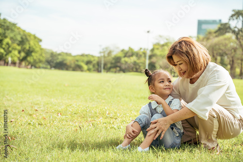Grandmother and grand daughter enjoying sunny garden holiday together, outdoors space, leisure lifestyle,happy teaching with flare light sky in park.