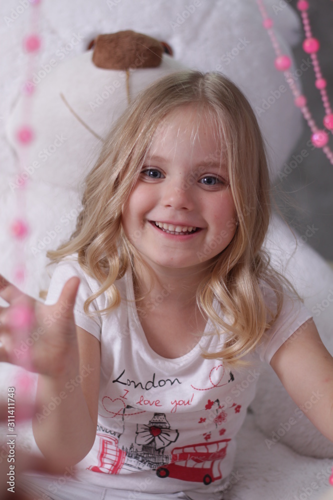 girl sitting on a big white teddy bear and playing with pink beads girl sitting on a big white teddy bear and playing with pink beads