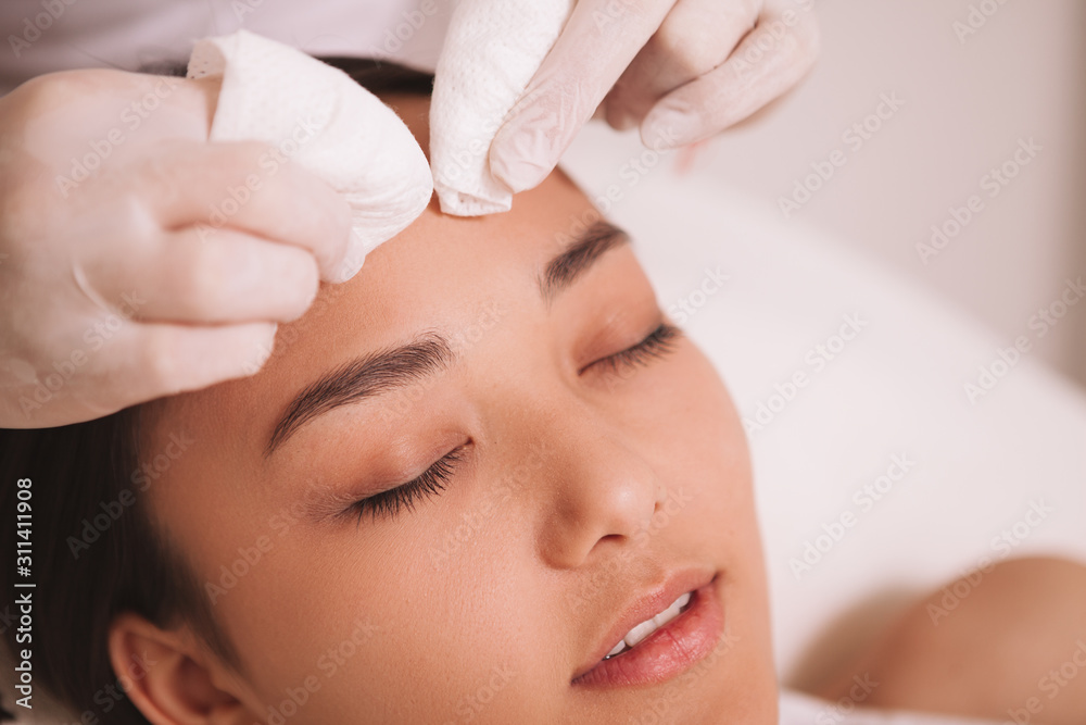 Cropped shot of a cosmetologist cleaning pores of a female client. Asian young woman having her skin cleansed by beautician