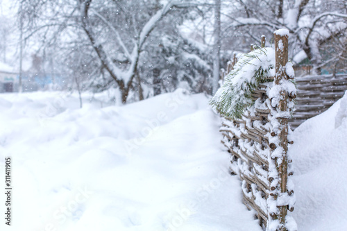 Winter old shabby wobbly wicker fence made of wooden boards. Snow blizzard