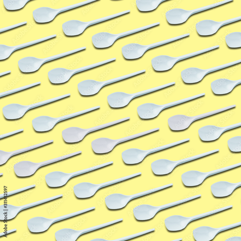 white plastic tea spoons pattern on yellow background