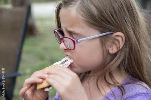 Young girl eating gooey marshmallow smoke
