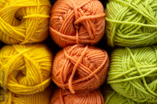 Multi-colored yellow, orange, lime green woolen threads in balls for knitting and handmade.