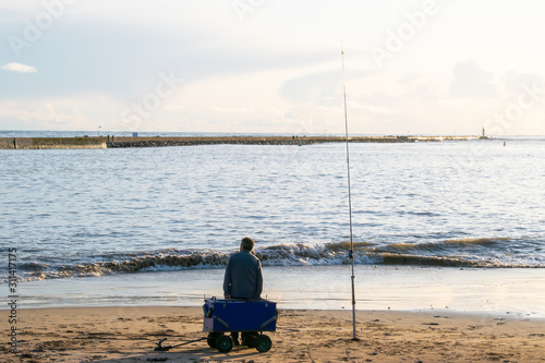 pêcheur à saint gilles croix de vie assis sur son chariot de pêche avec sa canne à lancer pêche dans le canal 