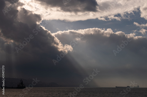 Lights falling into the city among the clouds. Dance of lights in Izmir Bay. ...