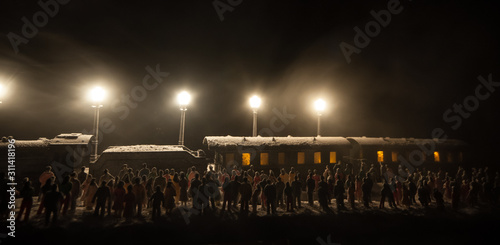 Silhouettes of a crowd standing at old vintage train on foggy background. Selective focus. Creative artwork decoration with toy train