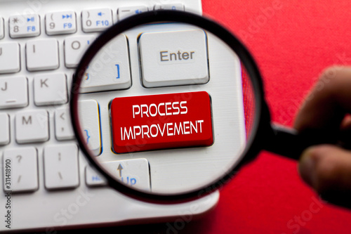 PROCESS IMPROVEMENT word written on keyboard view with magnifier glass photo