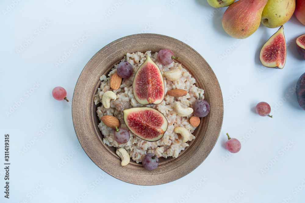 Oatmeal in a plate with fresh figs, almonds and cashews. Oatmeal with fruits. Healthy breakfast. Healthy food balance. Prepare food. White background. Oatmeal in a plate with fresh figs, almonds and cashews. Oatmeal with fruits. Healthy breakfast. Healthy food balance. Prepare food. White background.