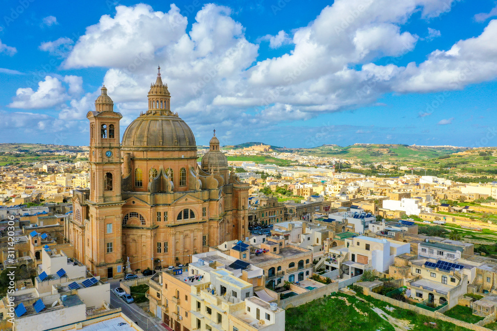 Aerial view oа St. John Baptist Church. Countryside of Gozo island, cloudy blue sky. Europe. Malta 