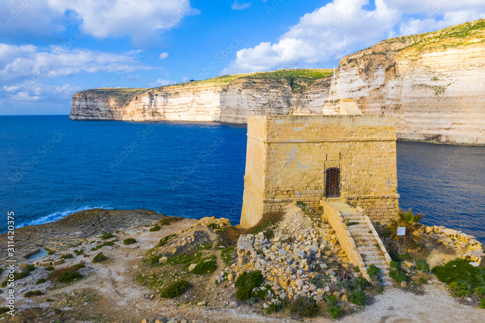 Aerial view of Xlendi tower, beach, bay on Gozo island. Salt pans and sea. Malta island