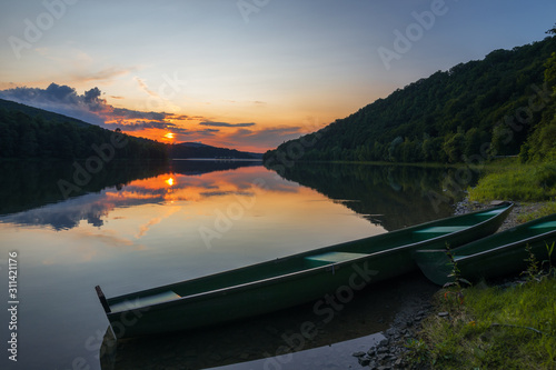 green boat on the shore of the lake at sunset