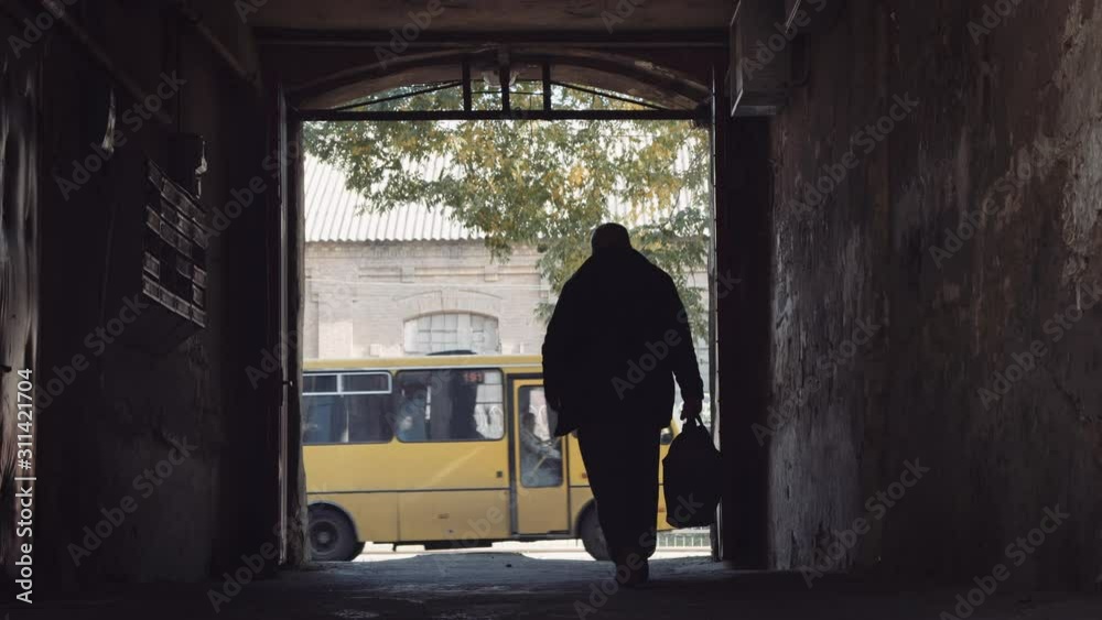 Man carrying duffel bag walks through dark tunnel in slow motion as bus passes Man carrying duffel bag walks through dark tunnel in slow motion as bus passes
