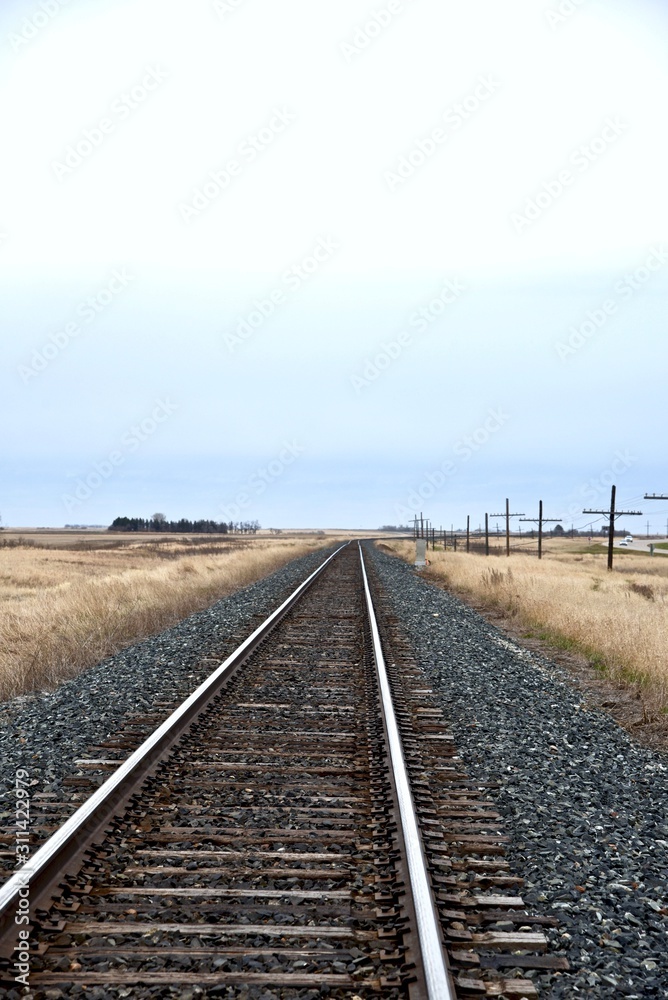 A railway track in the prairies leads to the horizon