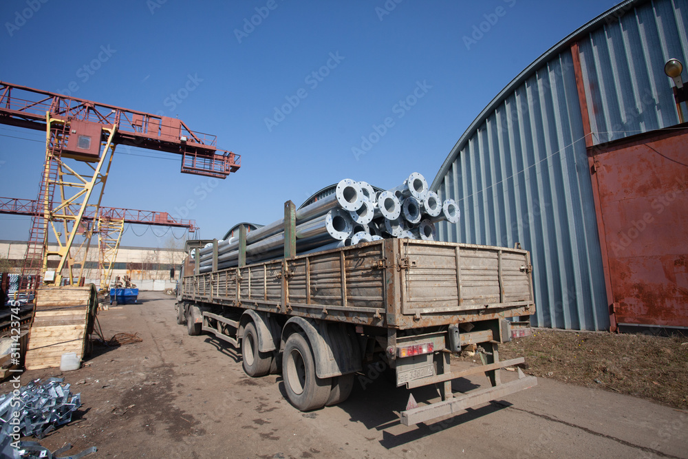 Metal warehouse outdoor of lighting poles. Storage of metal galvanized faceted pipes with flange.