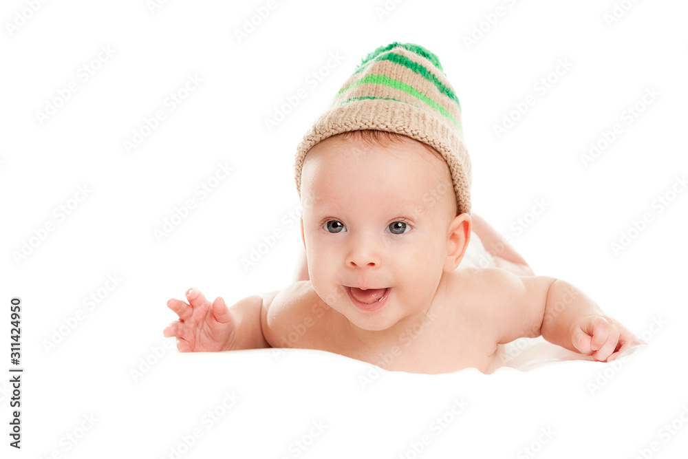 baby newborn lying on her stomach on the bed in a funny knitted hat isolated on white background, the concept of choosing baby clothes, washing and care baby newborn lying on her stomach on the bed in a funny knitted hat isolated on white background, the concept of choosing baby clothes, washing and care