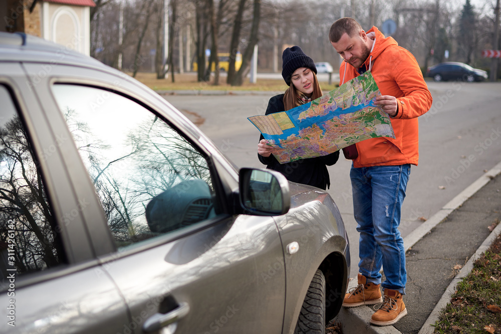 Map in the hands of young people on the road with a car. Map in the hands of young people on the road with a car.
