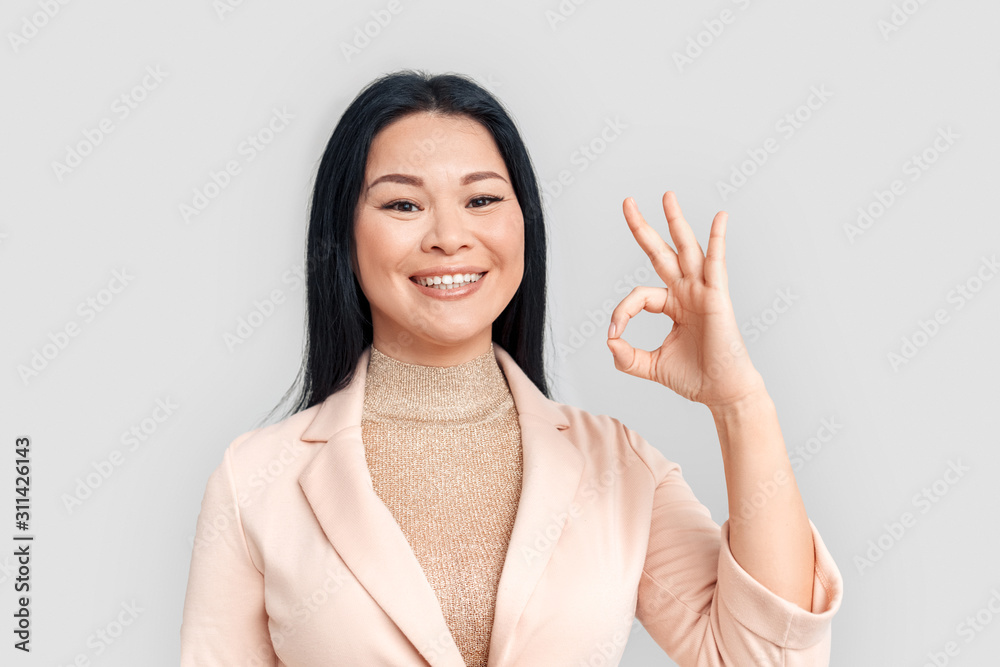 Freestyle. Asian businesswoman standing isolated on white showing ok to camera smiling cheerful close-up Freestyle. Asian businesswoman standing isolated on white showing ok to camera smiling cheerful close-up