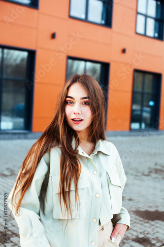 young pretty teenage girl posing cheerful happy smiling wearing street style outside in europe city, lifestyle people concept