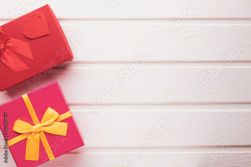 Top view two gift boxes with ribbons tied with a bow on a white wooden background with copy space: concept of a festive or romantic gift
