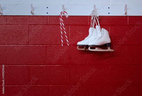 Christmas background of figure skates with candy cane hanging over red wall with copy space 
