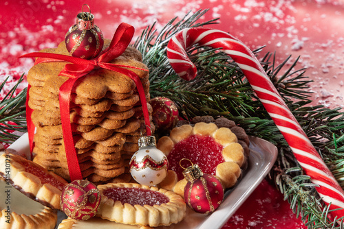 Christmas gingerbread cookie and candy cane on a plate among fir branches