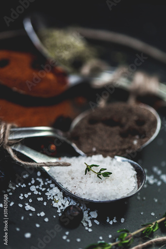 Spices in spoons. Closeup macro photo of salt, pepper and chili. Slate background. Rustic vintage color toning