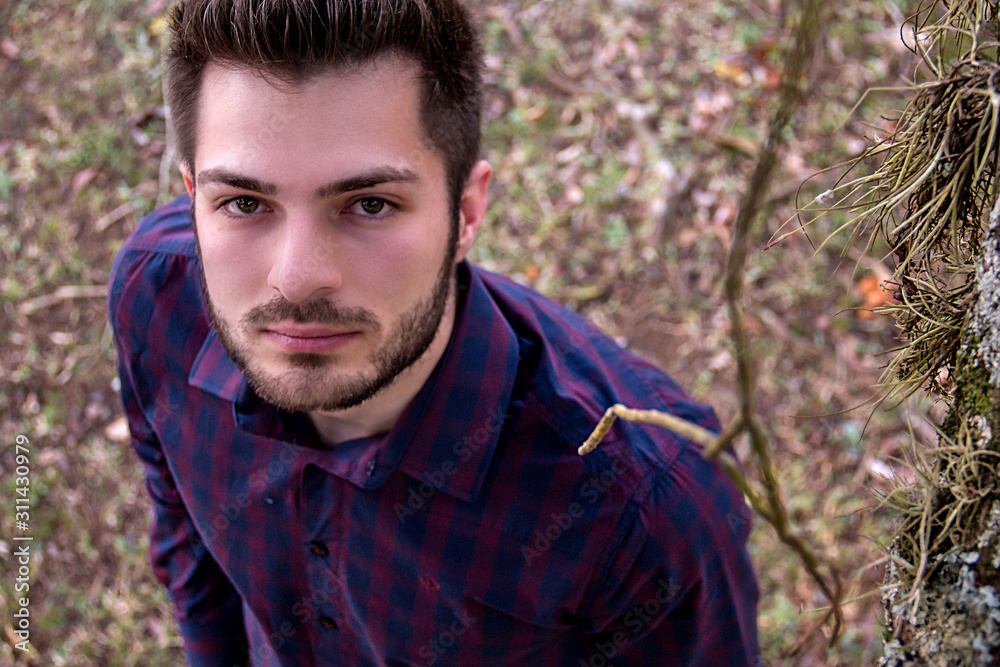 Handsome boy standing touching the trunk of a tree full of textures. Handsome boy standing touching the trunk of a tree full of textures.