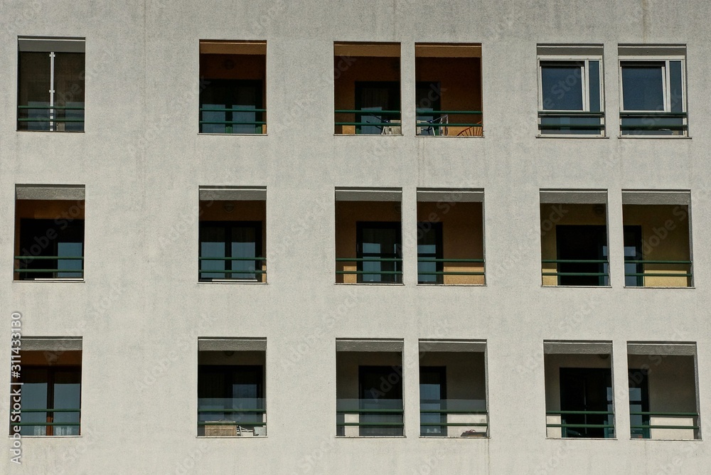 gray wall of a large house with rows of windows and balconies