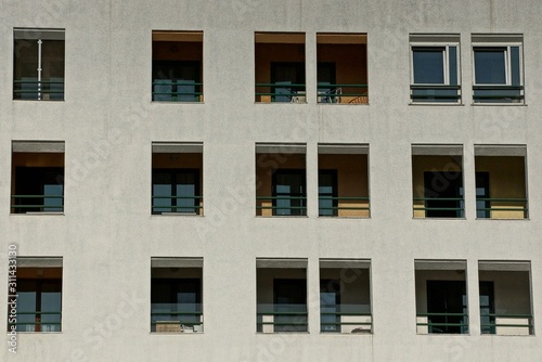 gray wall of a large house with rows of windows and balconies