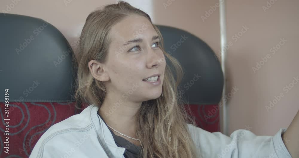 Woman in the train sitting and smiling while she is travelling Woman in the train sitting and smiling while she is travelling