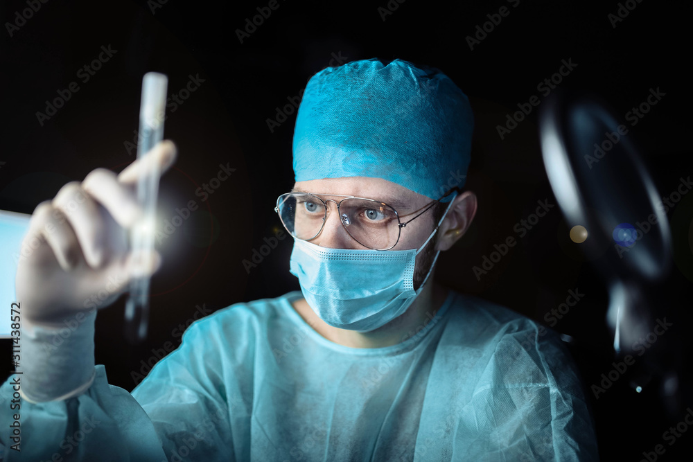 scientist doctor in a dark laboratory with a test tube of a medicinal product. scientist doctor in a dark laboratory with a test tube of a medicinal product.