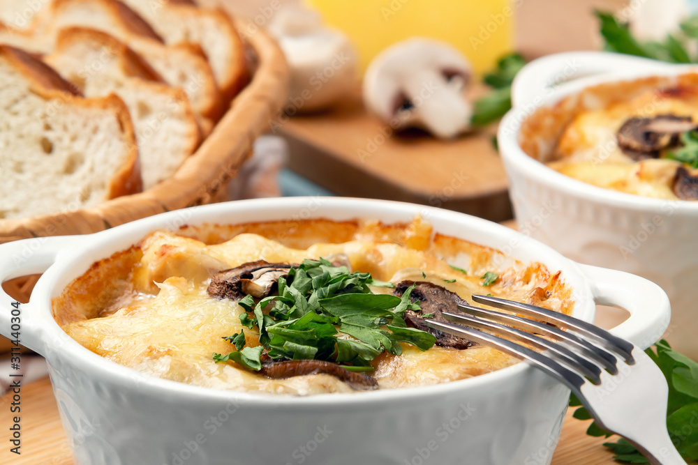 Casserole with chicken, mushrooms and cheese, known in Russia as julienne in white bowls with herbs, close up Casserole with chicken, mushrooms and cheese, known in Russia as julienne in white bowls with herbs, close up