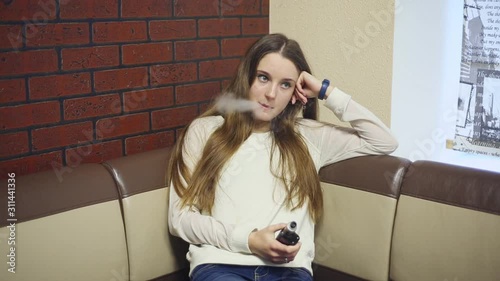 Vaping teenager with problem skin. Young cute caucasian girl smoking an electronic cigarette in the vape bar. Deadly bad habit. Vaping activity. Close up. Social problem.