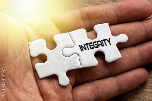 INTERGRITY written on White color of jigsaw puzzle with hand,conceptual