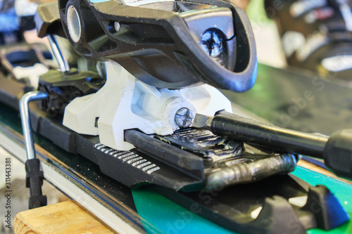 Obraz na płótnie Screw for adjusting forward pressure in a ski binding using a screwdriver, after clipping the ski boot in first. w salonie