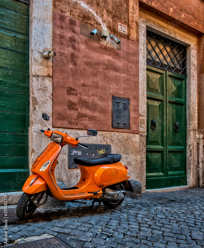 A pic of an orange scooter parked outside a door