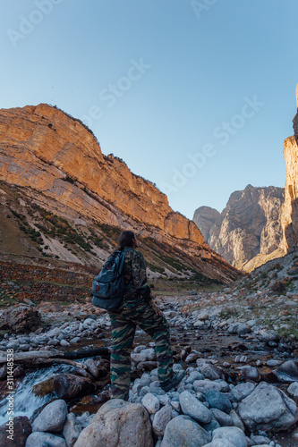 Male tourist in camouflage with backpack walking through mountain canyon