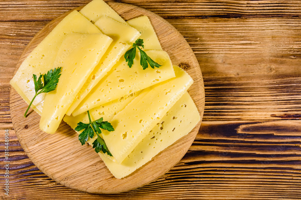 Sliced cheese and parsley on a wooden cutting board. Top view Sliced cheese and parsley on a wooden cutting board. Top view