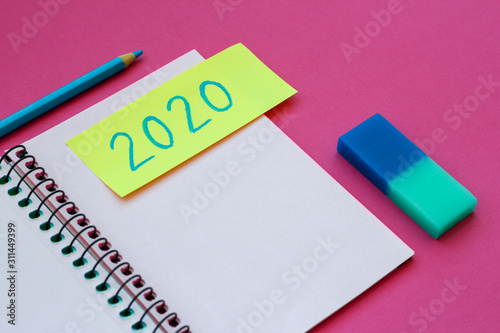 Colorful notebook with 2020 New Year's resolutions, pencil and eraser, with pink background and color block. modern minimalist
