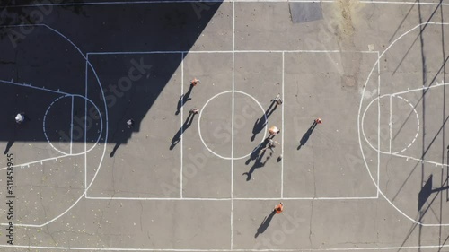 Overhead view of teenagers playing soccer football on asphalt court drone aerial