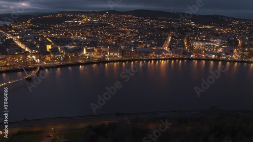 Londonderry / Derry / Stroke City / Legenderry night time aerial footage in UHD. Cityscapes of the Peace Bridge, The Foyle River, Guildhall, St Columb's Cathedral, Shipquay Street, Craigavon Bridge photo