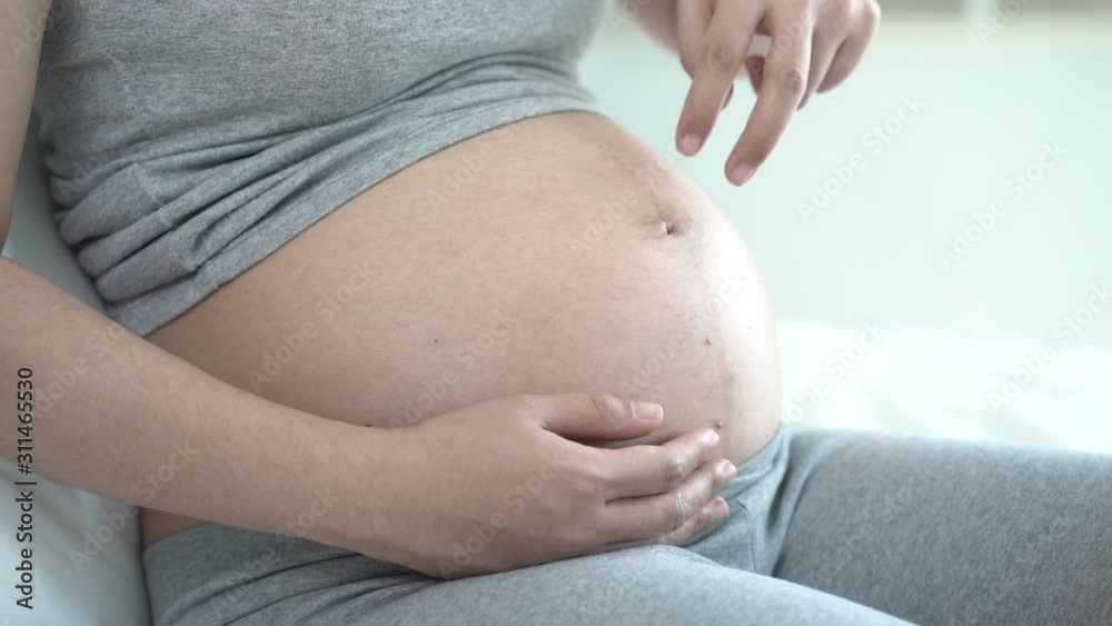 Pregnant woman lying and play fingers walk on her tummy.
