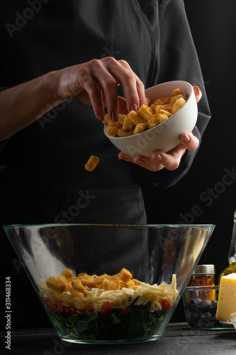 A professional chef cooks a fresh and healthy Italian salad sprinkling crackers, Freezing in motion. Organic and wholesome food. Healthy nutrition and vitamins. Advertising photo, vertical shot.