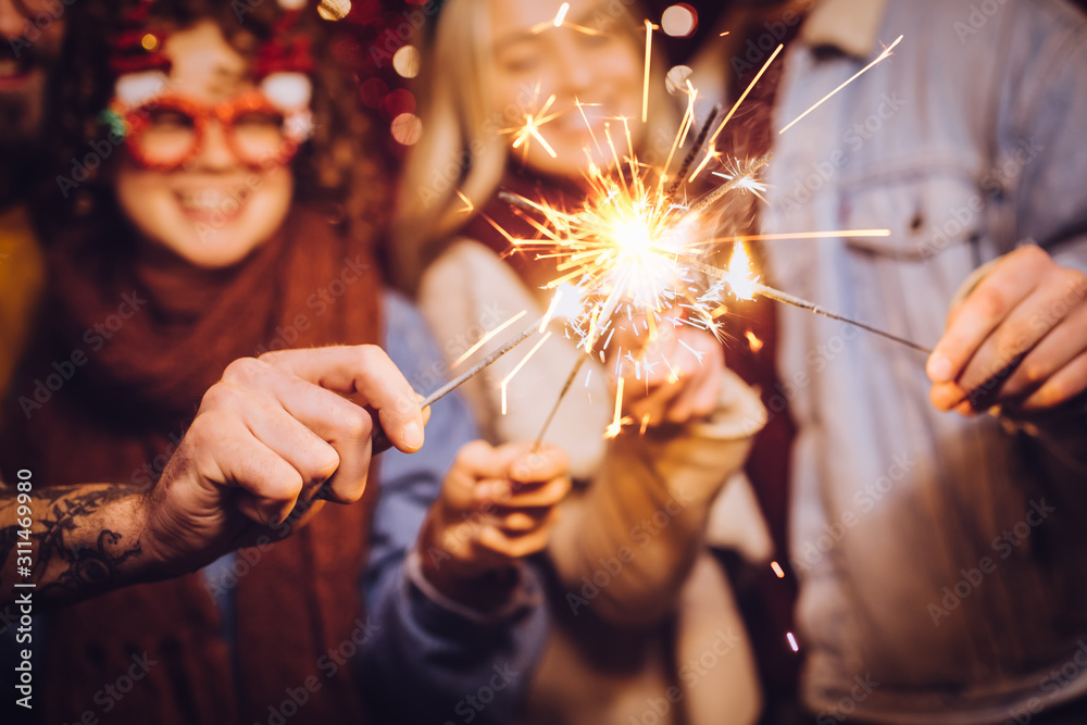 Close view of sparklers. Group of happy friends celebrating New Year with sparklers. New year party. - obrazy, fototapety, plakaty 