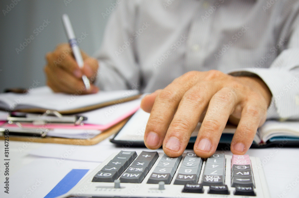 Business man using calculator and holding money for calculate tax in office. Business man using calculator and holding money for calculate tax in office.