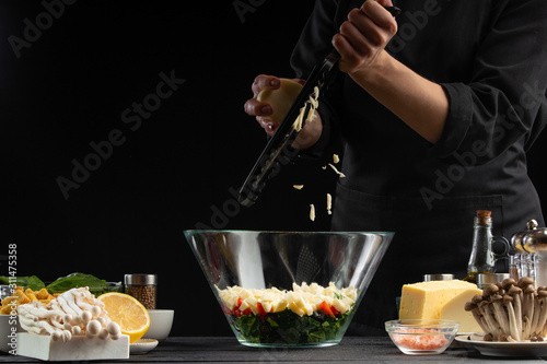 A professional chef cooks a fresh and healthy Italian salad grating mazarella cheese, Freezing in motion. Organic and wholesome food. Healthy nutrition and vitamins.