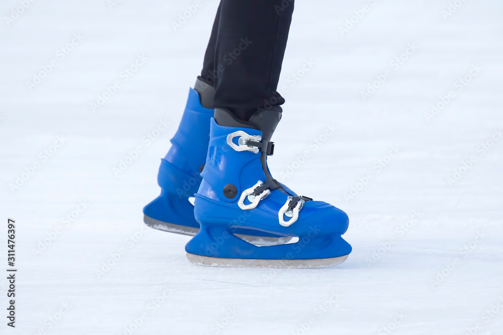 legs of a man in blue skates rides on an ice rink. Hobbies and sports. Vacations and winter activities. legs of a man in blue skates rides on an ice rink. Hobbies and sports. Vacations and winter activities.