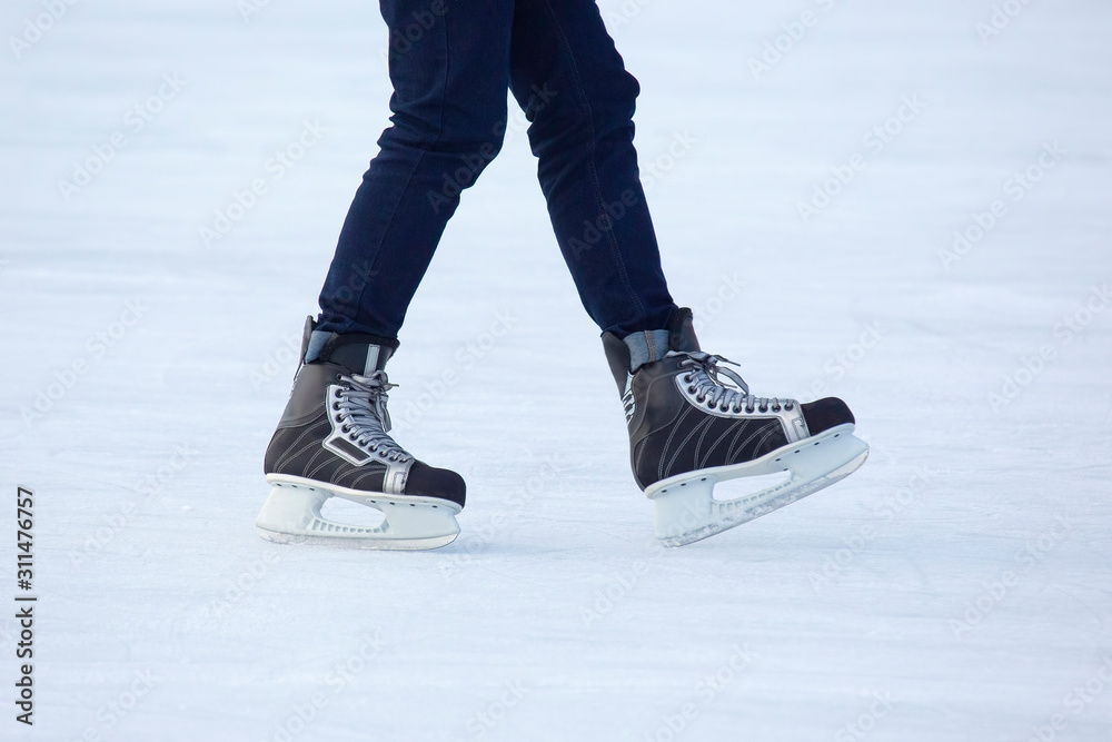 Legs of a man skating on an ice rink. Hobbies and sports. Vacations and winter activities Legs of a man skating on an ice rink. Hobbies and sports. Vacations and winter activities