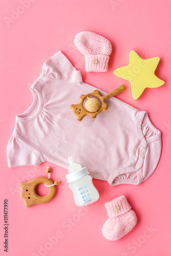 Pink bodysuit for baby girl near children's things on pink background top-down © 9dreamstudio