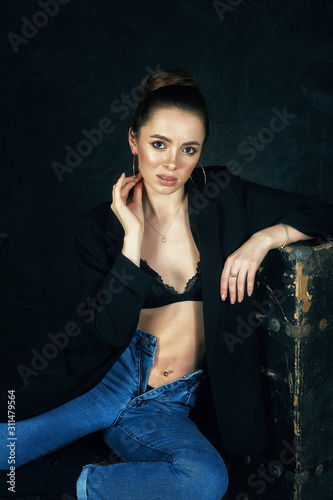 Young beautiful woman in Studio in jeans on dark background